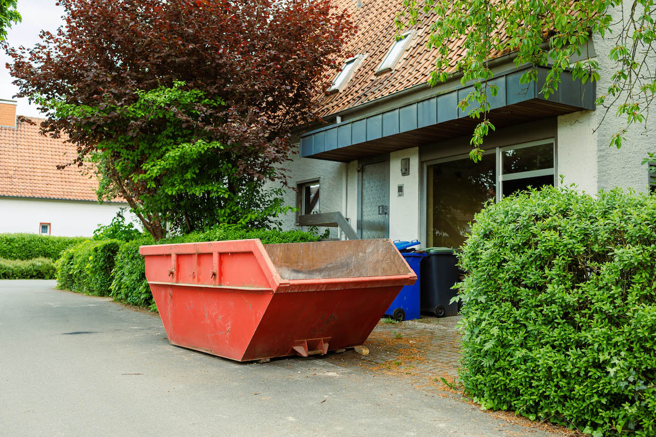 Uncollected skip waiting to be filled outside a driveway